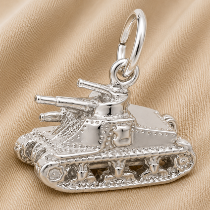 A gleaming Sterling Silver Tank Charm by Rembrandt Charms, complete with intricate treads and cannons, rests on beige fabric. This eye-catching piece of military jewelry includes a convenient loop for easy attachment to a chain or bracelet, making it a meaningful gift for veterans or a treasured collector’s keepsake.