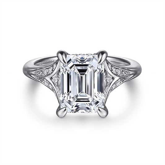 The Gabriel & Co 14K White Gold Split Shank Emerald Cut Diamond Engagement Ring features a stunning emerald-cut center stone with delicate diamond accents, all beautifully set in white gold.