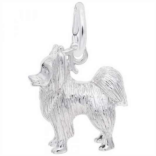 The Rembrandt Charms Papillon Dog Charm in sterling silver depicts a small dog with long, textured fur. The charm features a loop at the top for easy attachment to a bracelet or necklace, and the dog is standing on all four legs, facing sideways.