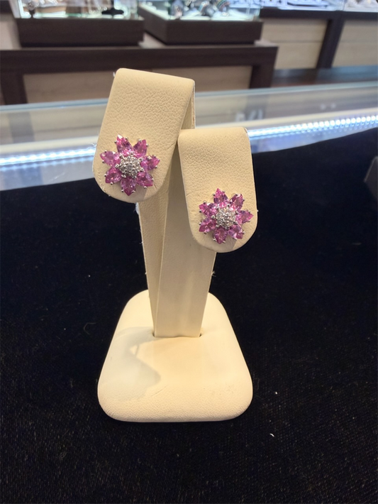 Pink Sapphire Flower Studs by Ryan Gems, crafted in 14k white gold with pink sapphire and white gemstones, displayed on a cream-colored stand in a jewelry store.