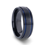Introducing the SHERIFF by Thorsten: a sleek black titanium men's wedding ring featuring two thin blue grooves circling its circumference. The words "BLACK TITANIUM" are subtly engraved on the inside of the band. This ring boasts a modern and sophisticated design with a brushed finish.