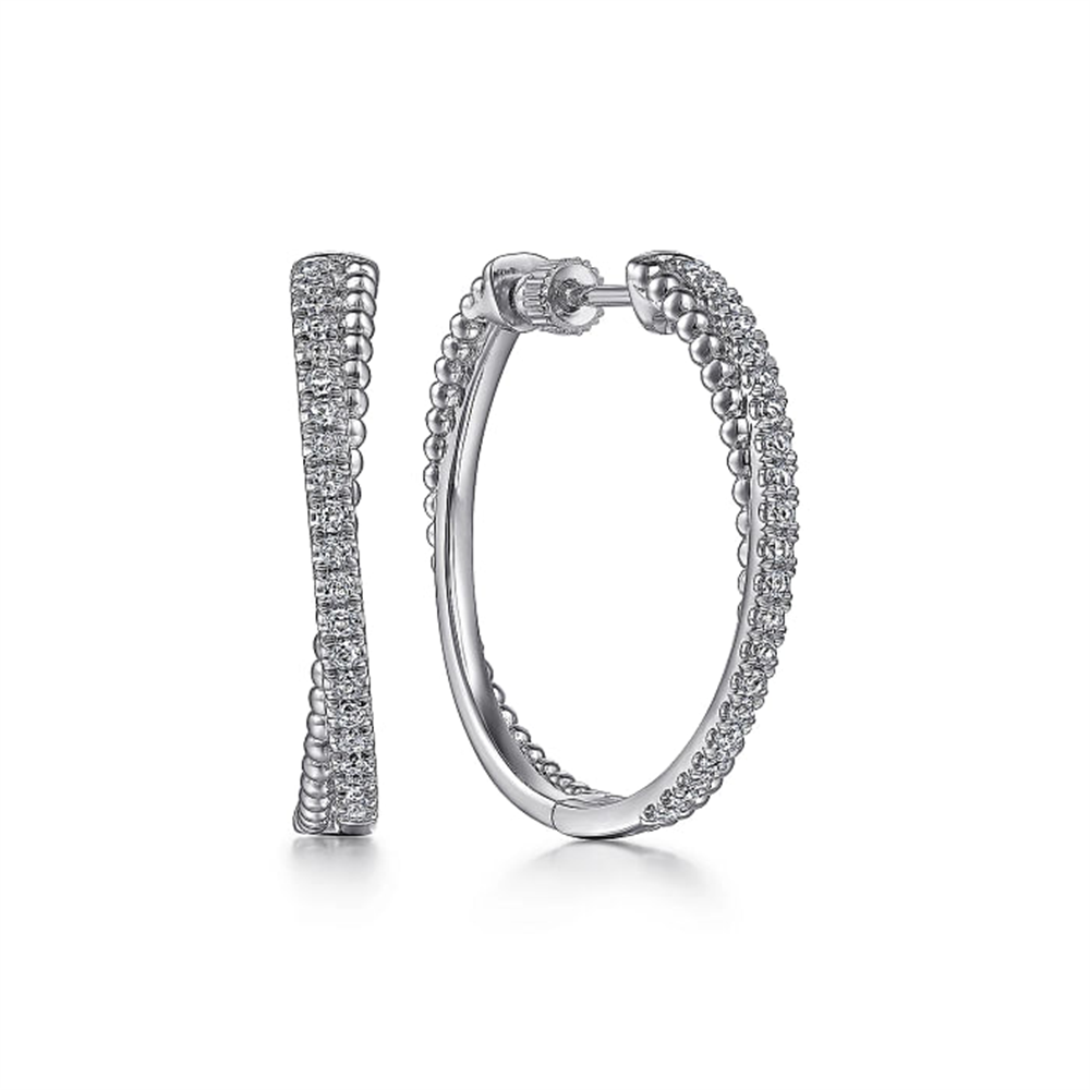 A pair of elegant, classic 925 Sterling Silver White Sapphire Twisted Bujukan 30mm Hoop earrings by Gabriel & Co. One earring is shown side-on, revealing a straight line of white sapphires, while the other is displayed in an open position showcasing the circular shape and intricate detailing.