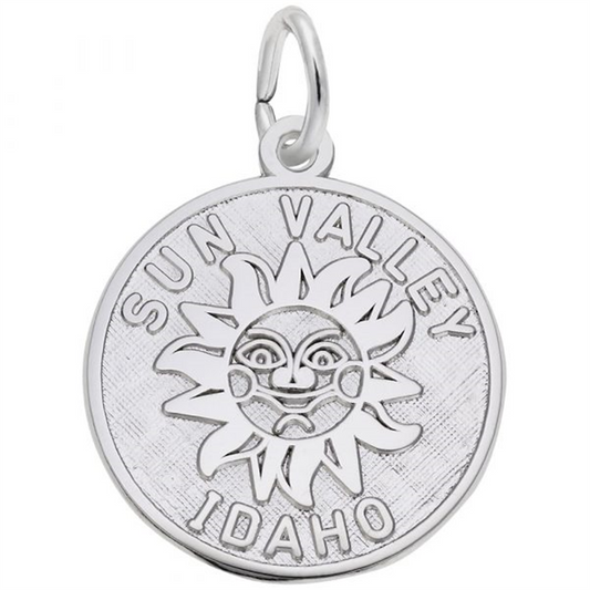 The Sun Valley Idaho Disc Charm by Rembrandt Charms is a sterling silver pendant featuring an engraved smiling sun with detailed facial features. The words "SUN VALLEY" are inscribed above the sun, and "IDAHO" below it. This charm includes a loop at the top for attaching to a chain or keyring.