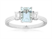 A stunning 14K white gold engagement ring from Royal Jewelry, Style # WH2016Q, features an emerald-cut aquamarine at the center accented by two smaller rectangular diamonds. The sleek and polished band discreetly bears a subtle logo on the inner side, embodying timeless elegance and sophistication.