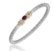 The Garnet and Diamonds Bracelet by Alwand Vahan Jewelry is a sterling silver piece with a textured design that showcases an intricate pattern. Its center boasts a garnet gemstone set in a 14K yellow gold accent, exuding sophistication and luxury against its pure white background.