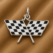 The Rembrandt Charms Racing Flag Charms—crafted in sterling silver and featuring two crossed black-and-white checkered flags—rest on a textured brown fabric background, making them an ideal motorsports gift for any enthusiast.