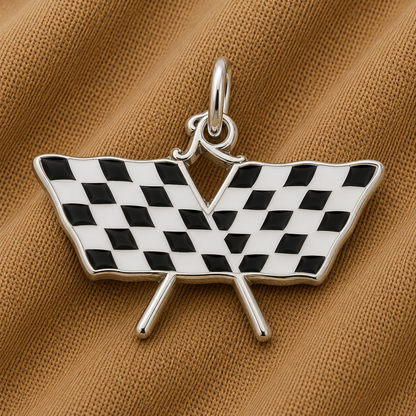 The Rembrandt Charms Racing Flag Charms—crafted in sterling silver and featuring two crossed black-and-white checkered flags—rest on a textured brown fabric background, making them an ideal motorsports gift for any enthusiast.