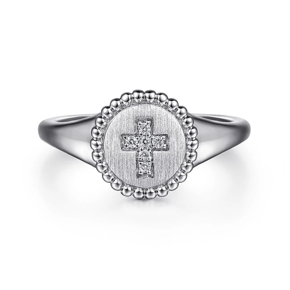 The Sterling Silver Signet Ring with Diamond Cross from Gabriel & Co's Bujukan Collection showcases a polished round band and features a circular, textured face adorned with a diamond-studded cross at the center, all encircled by a border of small, raised bead-like details.