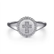 The Sterling Silver Signet Ring with Diamond Cross from Gabriel & Co's Bujukan Collection showcases a polished round band and features a circular, textured face adorned with a diamond-studded cross at the center, all encircled by a border of small, raised bead-like details.