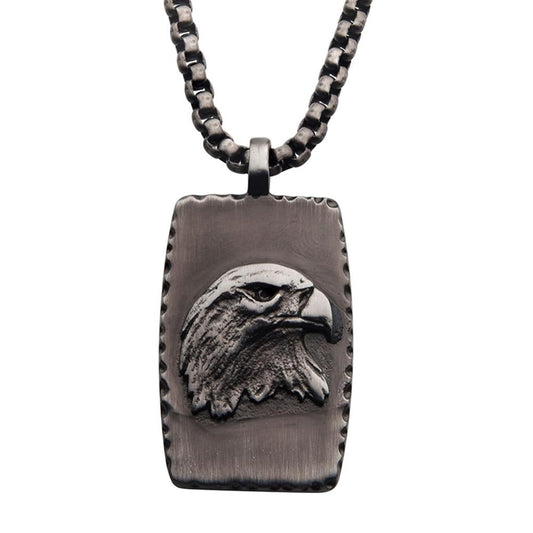 The Gun Metal IP Eagle Inlay Dog Tag Pendant with Round Box Chain by INOX features a rectangular, gun metal plated men's dog tag pendant adorned with a detailed eagle inlay. The pendant boasts a rugged, textured border that highlights the eagle's prominent and aggressive features, all hanging from a thick, linked chain.