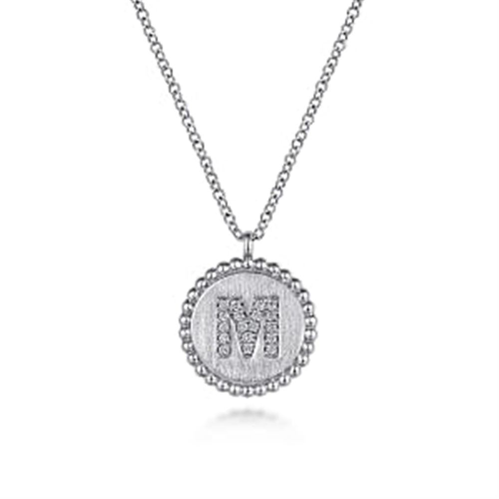 Presenting the Gabriel & Co. 925 Sterling Silver Diamond Bujukan Initial "M" Necklace. This exquisite piece features a round pendant adorned with small diamonds, gracefully hanging from a fine chain and bordered by a delicate scalloped edge of tiny diamonds. The intricate details of the jewelry are elegantly set against a plain white background to highlight its sophistication.