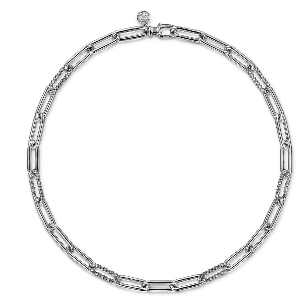 A close-up of the 925 Sterling Silver Oval Link Chain Necklace with Bujukan Stations by Gabriel & Co reveals its elongated, rectangular links. This sleek and minimalist piece from the Bujukan Collection features a clasp adorned with a round accent near the closure and includes sections of smaller, textured links for added detail.