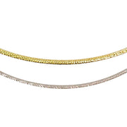 Close-up image of two elegant chains. The top chain, a Bellarri 14kt Reversible Omega Chain in 14KW / 14KY with a length of 17" and a 2" extender, showcases its gold hue, while the bottom chain gleams in silver. Both chains feature a textured surface that reflects light beautifully, giving them a shimmering appearance. The background is plain white.