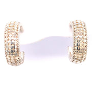 The Sterling Silver Dome Hoop Earrings from Anna Beck Designs feature a gold-tone dome shape with a pebble-like pattern. The wide-band design showcases intricate, shimmering details that reflect light beautifully. Presented on a white background, these earrings highlight sterling silver accents that add an extra touch of elegance.