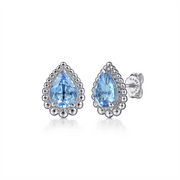 Introducing the Gabriel & Co 925 Sterling Silver Faceted Swiss Blue Topaz Pear Shape Bujukan Stud earrings. These stunning Boutique Silver earrings feature prominent, teardrop-shaped Swiss Blue Topaz gemstones at their center. The gemstones are elegantly encircled by small, round silver details, enhancing their detailed and ornate appearance. Visible sterling silver earring backs with the Gabriel & Co brand marking complete this exquisite pair.