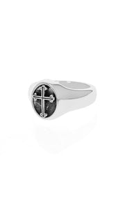 The Traditional Cross Silver Ring by King Baby is a polished and reflective signet ring showcasing a black circular face with an intricate cross design, set against a plain white background.