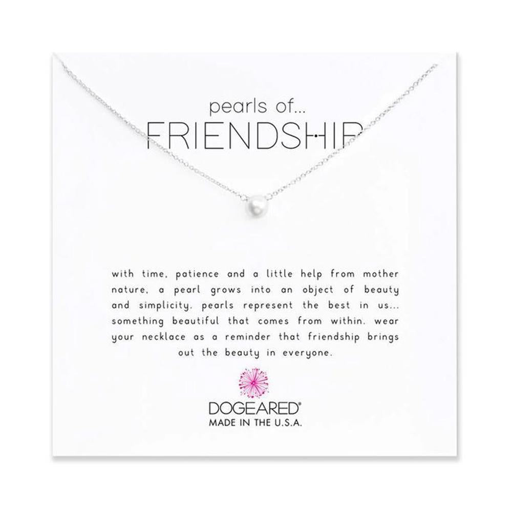 An 18-inch SS Necklace by Dogeared, featuring a single pearl pendant, sits on a card that reads: "Pearls of Friendship. With time, patience, and a little help from Mother Nature, a pearl grows into an object of beauty and simplicity. Pearls represent the best in us... Made in the U.S.A.