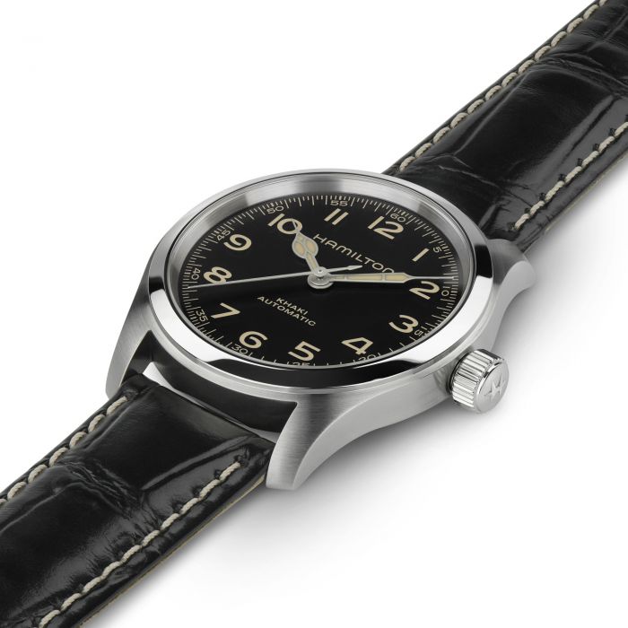 A close-up view of the Hamilton Khaki Field Murph 38mm wristwatch with a black leather strap. The watch showcases a stainless steel case, a black dial with Arabic numeral markers, and silver hands accented by a golden seconds hand. The word "Hamilton" is prominently displayed below the 12 o'clock position.