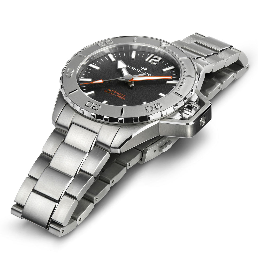 A close-up shot of a sleek silver Hamilton wristwatch with a metal band and a black face, featuring the Khaki Navy Frogman Automatic 46mm model. The watch boasts silver hour markers, orange-tipped hands, and a prominent rotating bezel. The brand name, Hamilton, along with the model name Khaki Navy Frogman Automatic 46mm and its high-precision timepiece movement are visible on the watch face.
