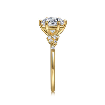 Side view of the Gabriel & Co 14K Y floral band engagement ring with a large CZ center stone in a four-prong setting, accented by small diamonds on the intricate gold design. Displayed on a white background.
