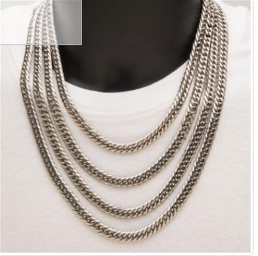 A close-up image showcases the "8mm Steel Dome Curb Chain | 24" | INOX," a men's stainless steel necklace from the brand INOX, draped elegantly across the chest and resting on a white shirt. This single-layered silver necklace accentuates the wearer’s style, highlighting the neck and upper chest area.