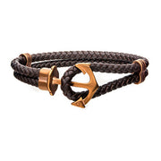 The Men's Cappuccino Plated Anchor Bracelet by INOX combines style with sophistication, featuring a brown braided cord and a shiny bronze anchor-shaped clasp. The intricately designed anchor adds nautical charm to this men's bracelet, with the leather cord looping through the anchor to secure this distinctive accessory.
