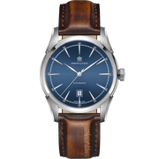 Introducing the Hamilton Spirit of Liberty Automatic Watch, a luxury timepiece featuring a blue dial, silver case, and brown leather strap. The watch showcases silver hour markers, a date window at 6 o'clock, and proudly displays the "Hamilton" brand name on the dial. Powered by an automatic movement, it embodies the Spirit of Liberty with "earth boat ship" elegantly embossed on the strap.