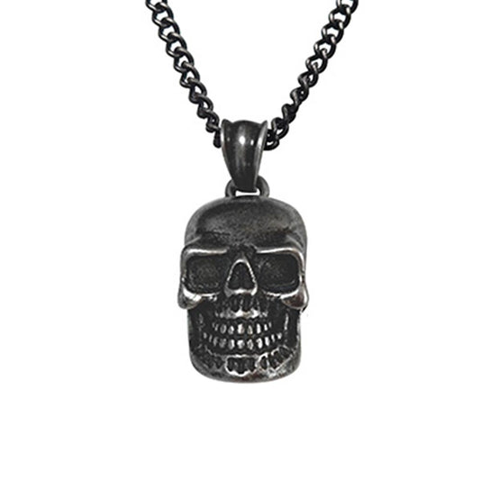 The Men's Stainless Steel Antique Gunmetal Skull Pendant by INOX features a dark stainless steel chain measuring 22 inches, with a detailed skull pendant. The skull has hollow eyes, prominent teeth, and a slightly aged, rustic finish that gives it a Gothic appearance. This piece of men's jewelry boasts a sturdy chain with interlocking links.