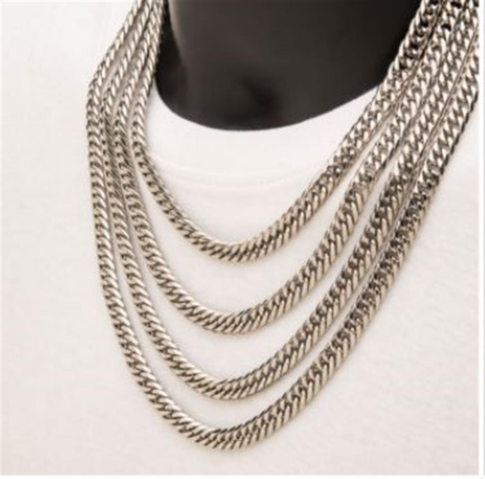 A close-up image of a person wearing the 8mm Steel Dome Curb Chain by INOX, layered beautifully around their neck. The chains, measuring 22 inches each, feature a robust design with thick, interlocking links. The person’s white garment provides a striking contrast to the metallic sheen of these men's stainless steel necklaces from INOX.
