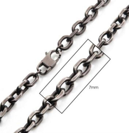 Close-up of a metallic 7mm Oxidized Steel Knife Edge Link Chain | 24" | INOX with oval links, a lobster clasp, and a labeled box highlighting a section of the chain. The text within the box reads "7mm," indicating the size of the chain links. This 24 inch necklace is displayed against a white background.