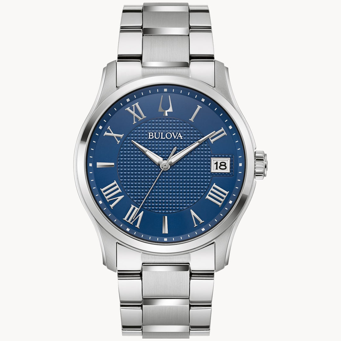The Bulova Watch Company's classic Wilton timepiece, model 96B386, showcases a sophisticated design with its blue textured 3-hand dial adorned with silver Roman numerals and a date window at the 3 o'clock position. It features a polished metal bracelet complemented by a stainless steel round case.