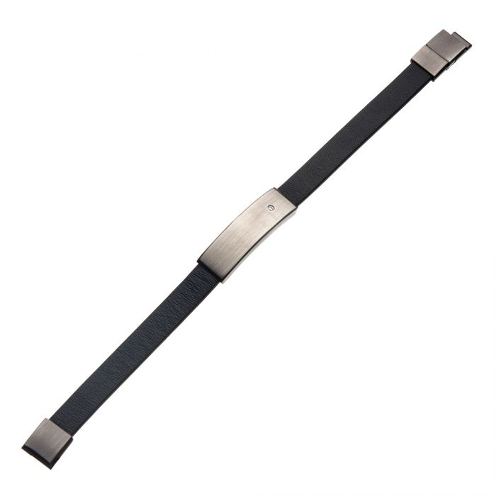 The Black Leather with 2mm Clear CZ in Engrave Steel ID Bracelet by INOX showcases a sleek design with a rectangular silver metal plate centered on the black leather strap, featuring a small diamond-like gem. The engravable ID bracelet is equipped with simple metal clasps on both ends for secure fastening around the wrist.