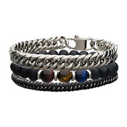 Presenting the Men's Black Braided Leather Bracelet by INOX: a stylish accessory featuring a thick silver chain, dual strands of black matte beads interspersed with polished stone beads in shades of brown, yellow, and blue, and a sophisticated black braided leather strand. This bracelet is secured with a clasp fastening mechanism.