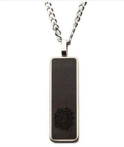 A striking Carbon Fiber & Steel Dog Tag Pendant by INOX, featuring a rectangular design with a black centered plaque and an intricate embossed lion at the bottom. This men's pendant comes with a 24-inch steel curb chain that perfectly complements its rounded edges and sleek, modern appearance.