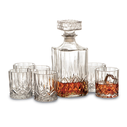 A 7 Piece Crystal Whiskey Set, consisting of six 6-8 oz glasses and a 32 oz decanter partially filled with amber liquid. The decanter comes with a square, faceted stopper, and all pieces feature an intricate cut-glass design. The glasses are arranged around the decanter.