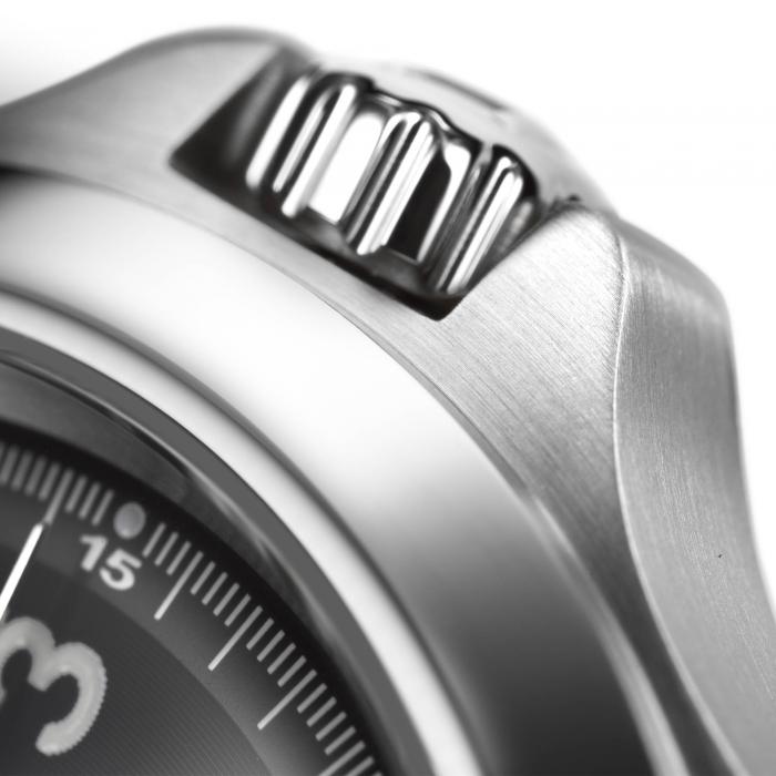 Close-up of a sleek, silver watch crown with a grooved and polished texture. The edge of the watch face, partially visible, shows detailed minute markings and the number 3, indicating a classic and precise design. The brushed metal finish adds an elegant touch to this Hamilton Khaki Field King Automatic Watch.