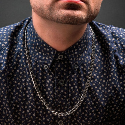 Close-up of a person wearing a blue patterned button-up shirt and a striking 4mm Steel Diamond Cut Curb Chain Necklace from INOX. The image highlights the lower half of the person's face, neck, and upper chest adorned with the intricate 22" men's stainless steel necklace.