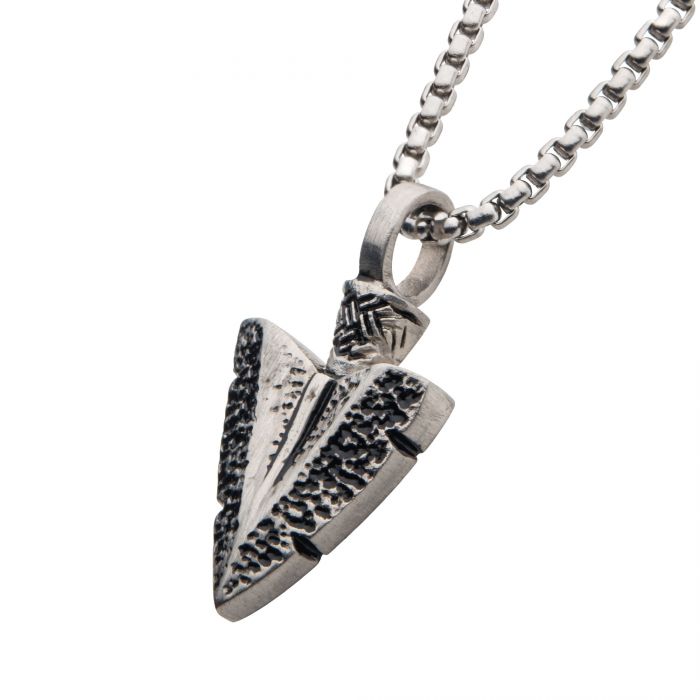 The INOX Antiqued Steel Arrowhead Pendant, featuring a detailed textured design, hangs from a bold 22-inch box chain. This elegant pendant combines polished and textured metal for a rustic yet sophisticated appearance.