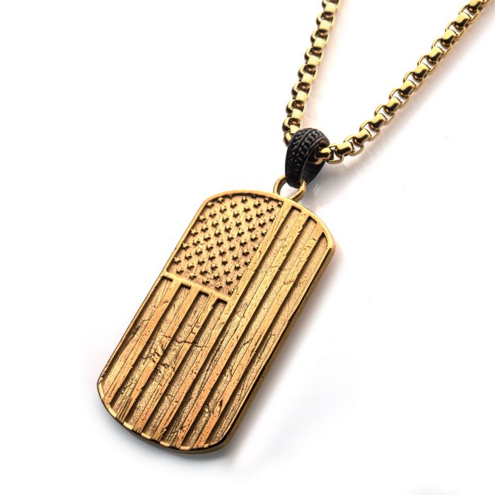 The Polished Gold Plated Rugged American Flag Pendant from INOX, featuring stars and stripes engraved on a polished black plated bail and hanging from a thick gold plated box chain, is displayed against a white background.